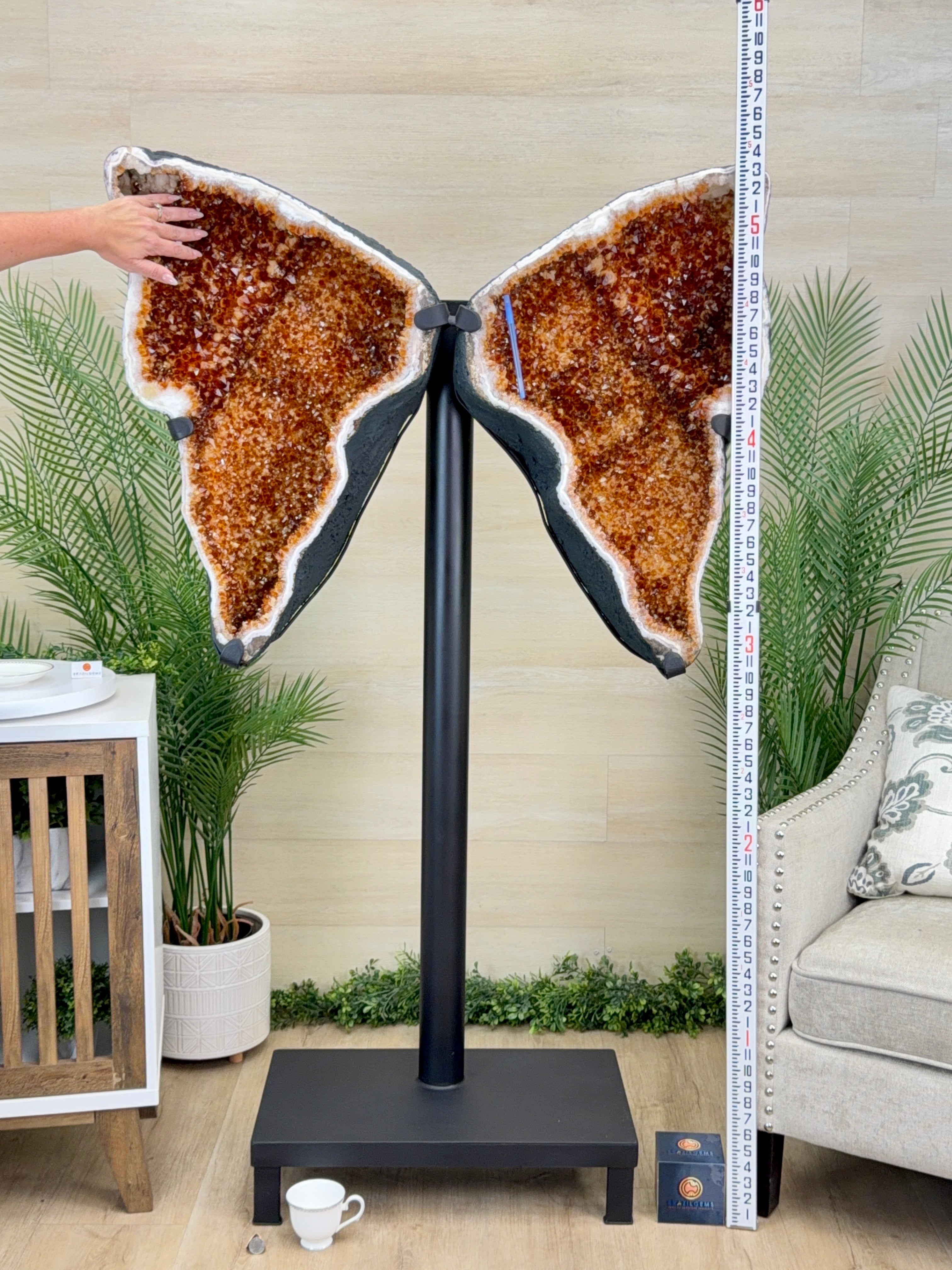Butterfly-shaped decorative piece on a stand with a measuring tape for scale, in a home setting.