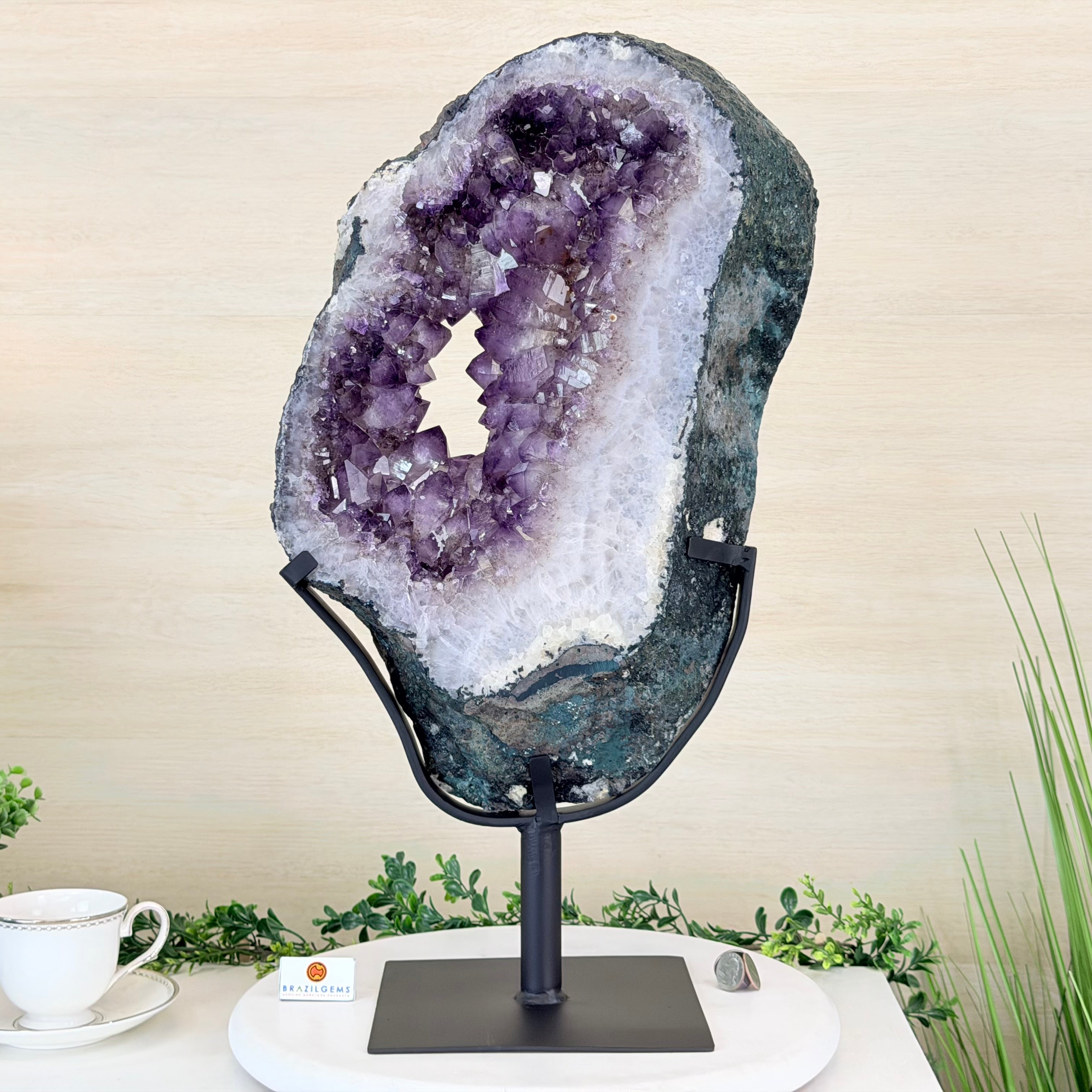 Amethyst geode on a stand with a cup and saucer in the background