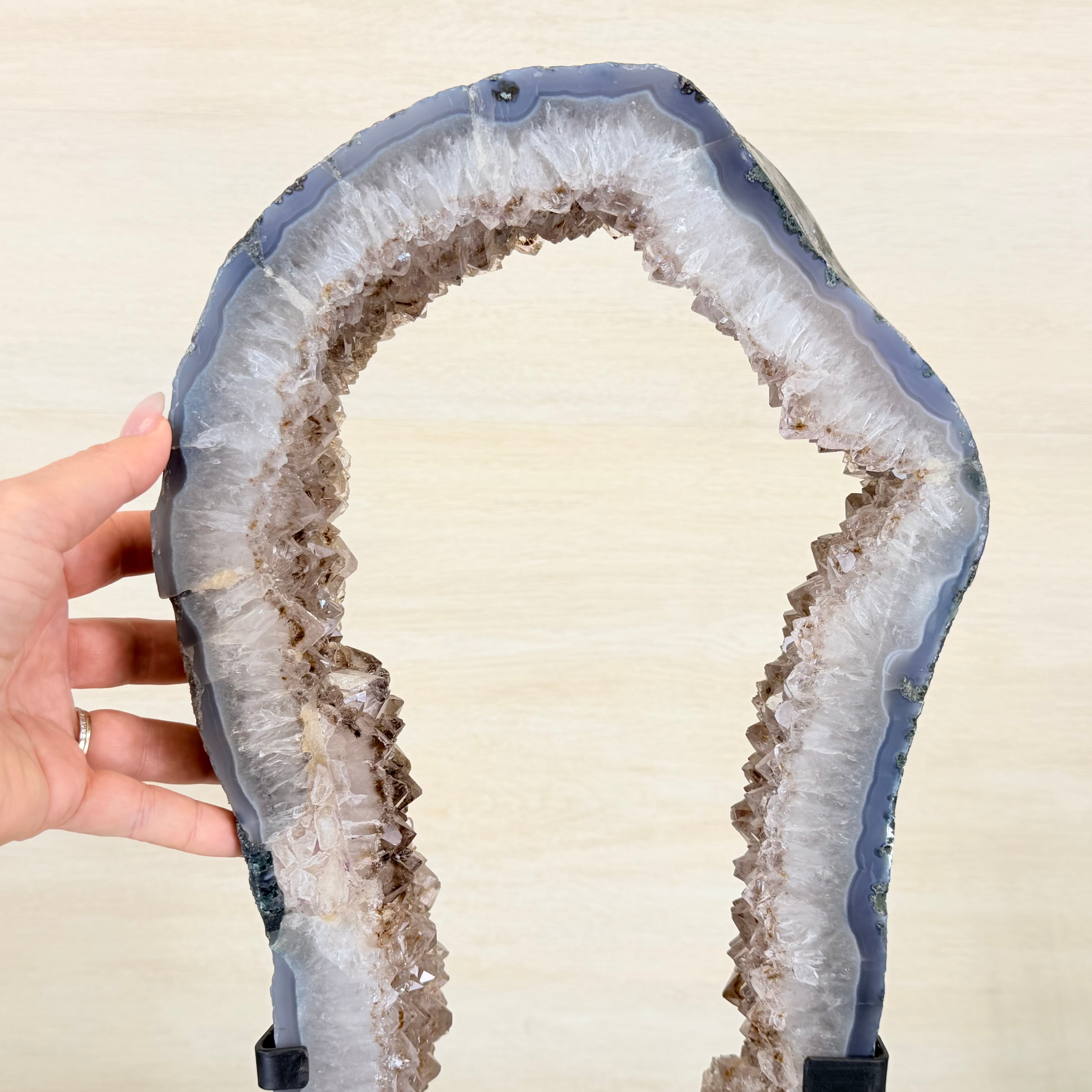 Geode crystal held by a hand against a beige background