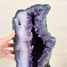 Amethyst geode held by a hand against a plain background