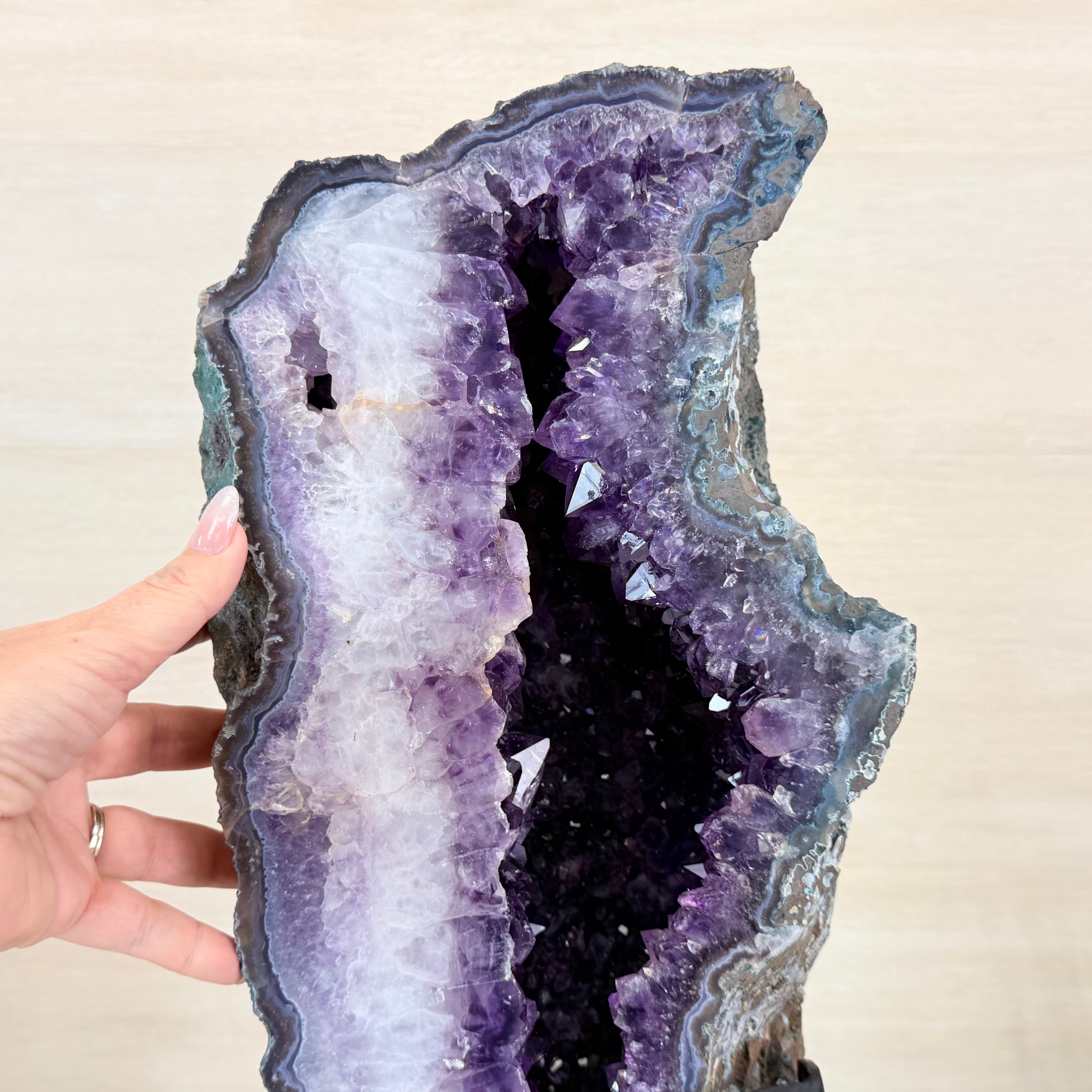 Amethyst geode held by a hand against a plain background
