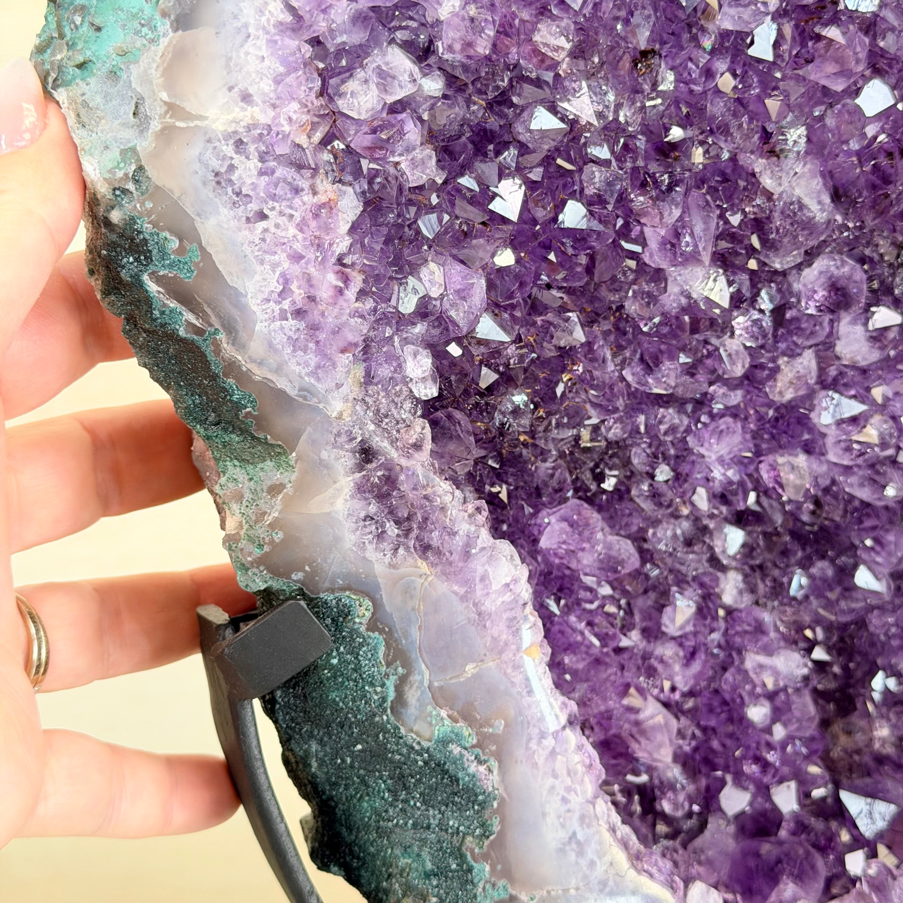 Close-up of a hand holding a USB cable against a purple crystal formation.