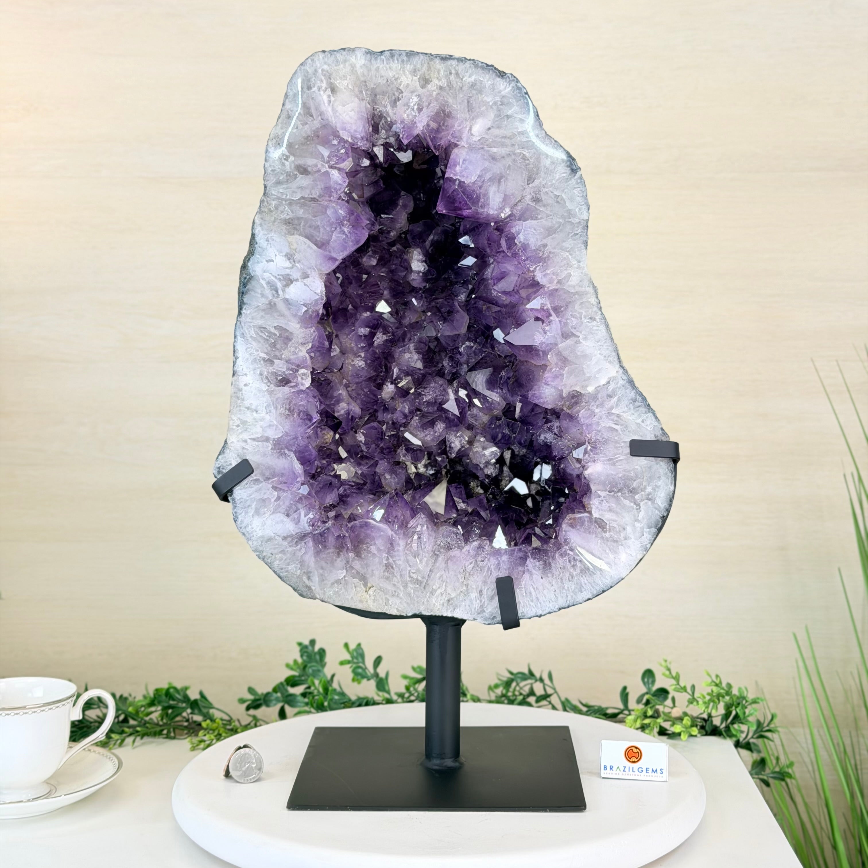Amethyst geode on a stand with a tea cup and saucer in the background