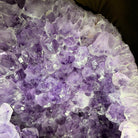 Close-up of a purple amethyst crystal cluster with translucent lavender and lilac crystals filling the frame.