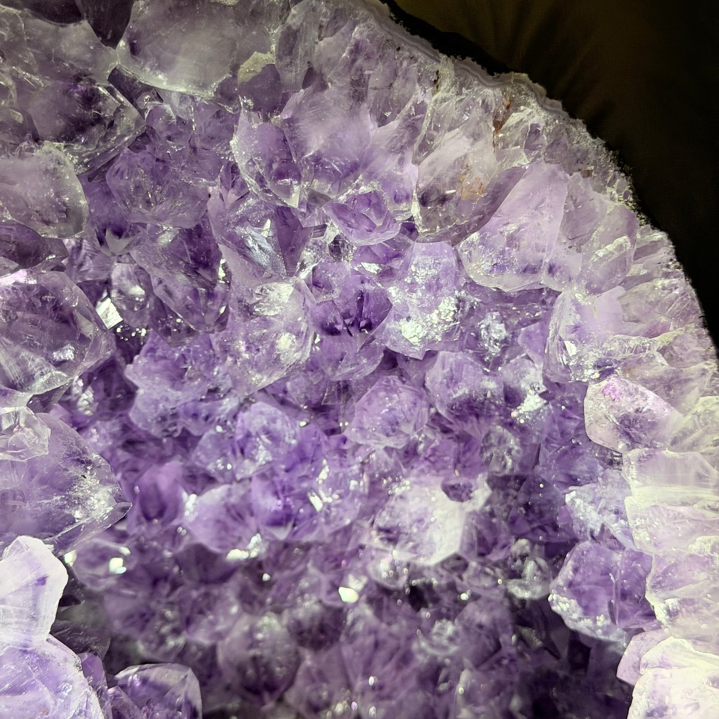 Close-up of a purple amethyst crystal cluster with translucent lavender and lilac crystals filling the frame.