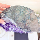 Close-up of a hand holding a geode with purple crystals inside.