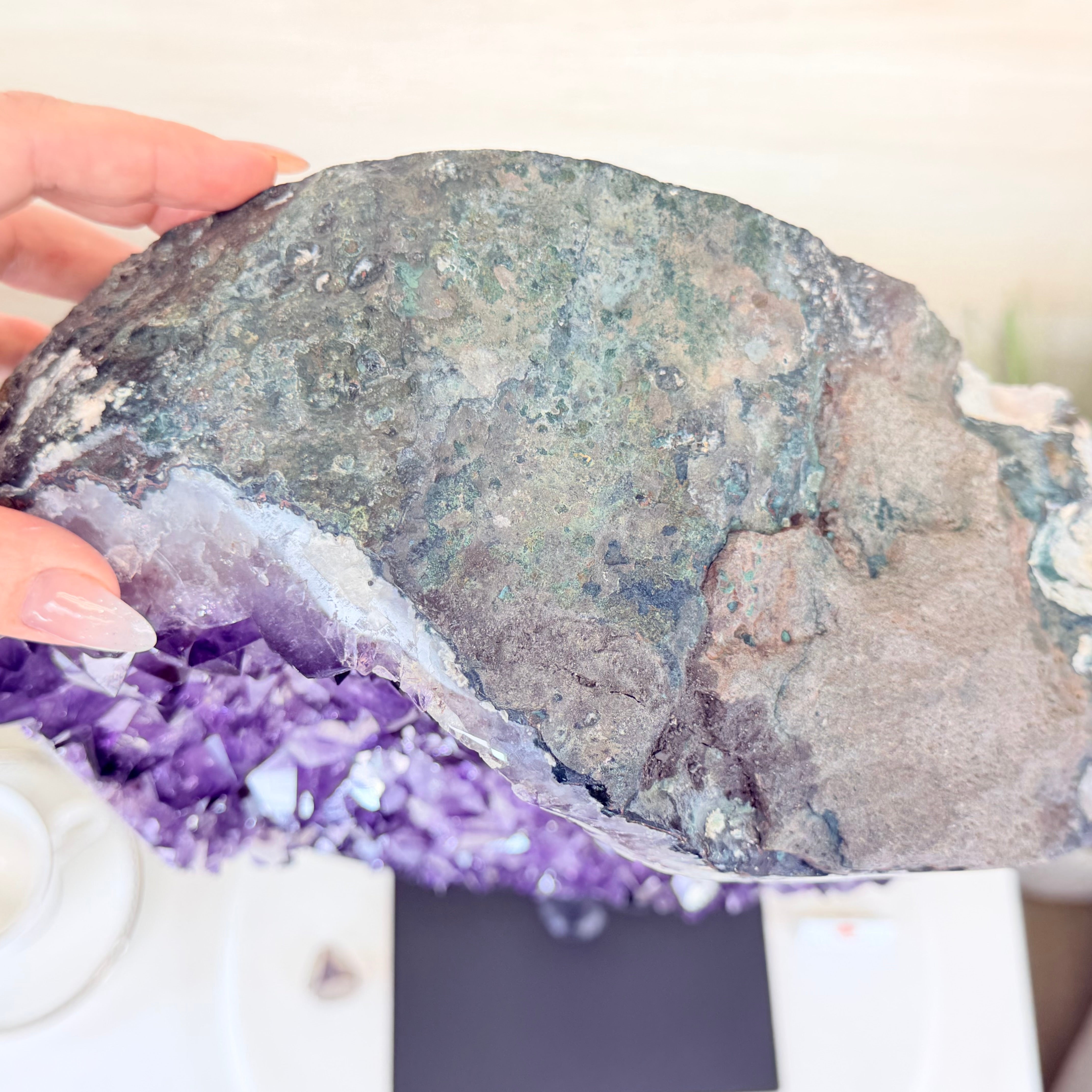 Close-up of a hand holding a geode with purple crystals inside.