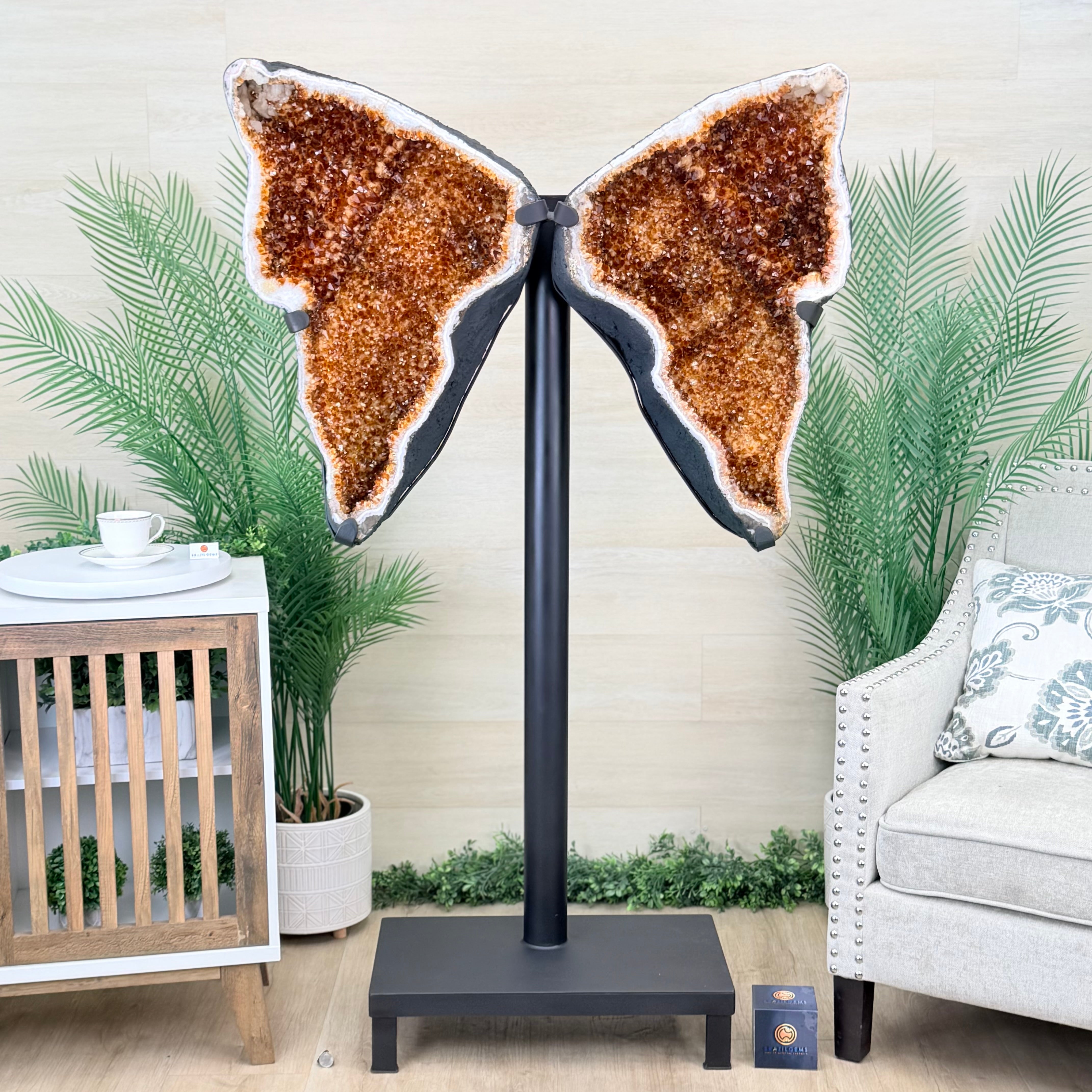 Butterfly-shaped decorative piece on a stand in a living room setting with plants and furniture.