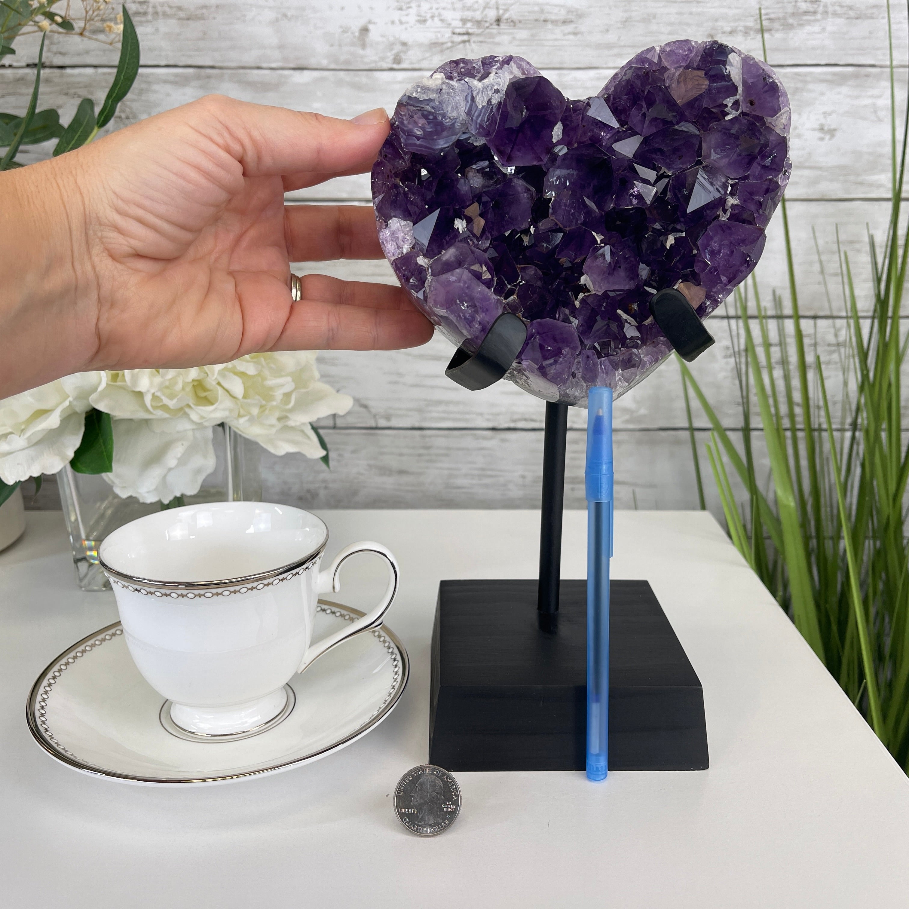 Individual showcasing the amethyst heart geode on a metal and wood stand