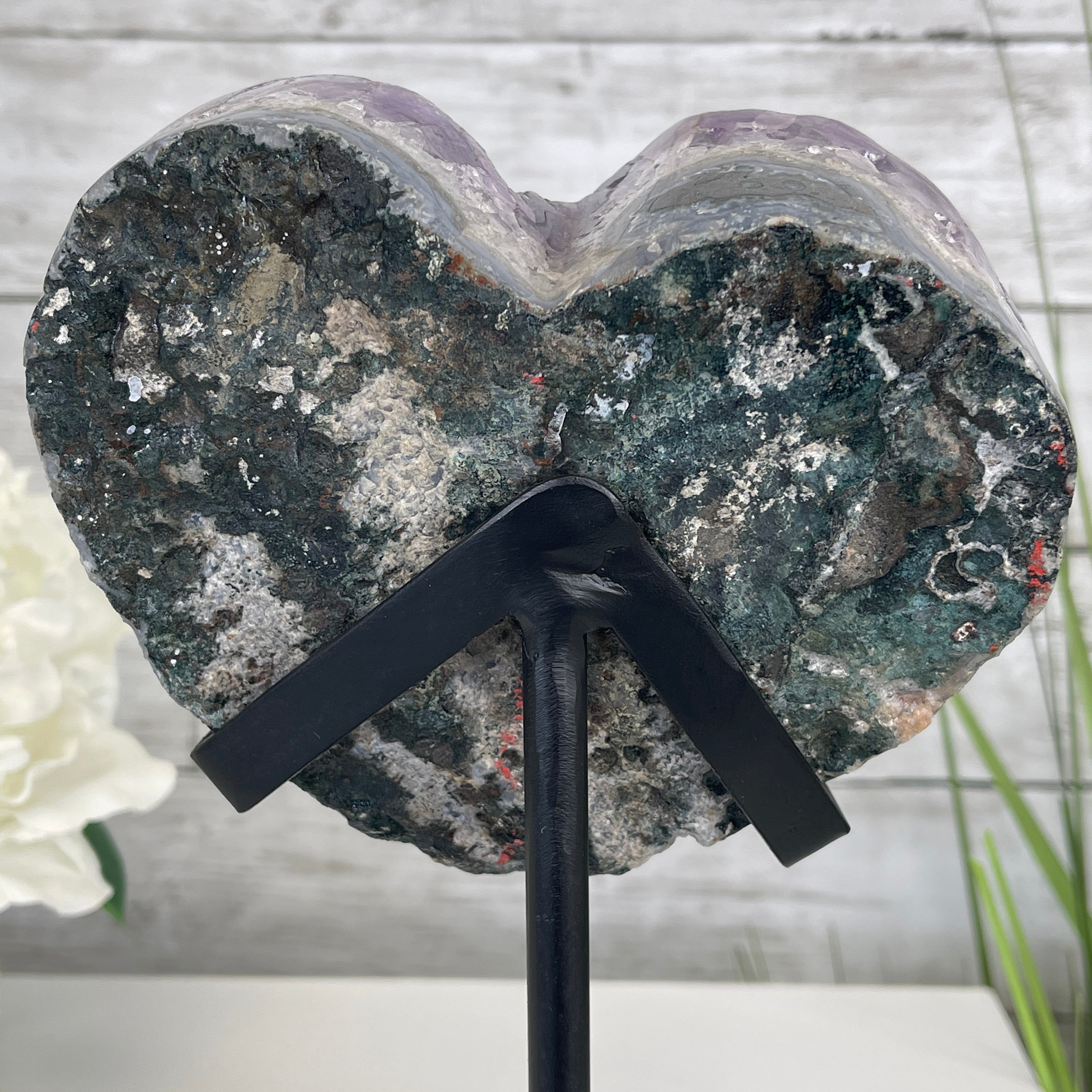 Heart-shaped Amethyst Geode displayed on a stand with flowers