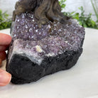 A hand holding an Amethyst crystal base of a gemstone tree