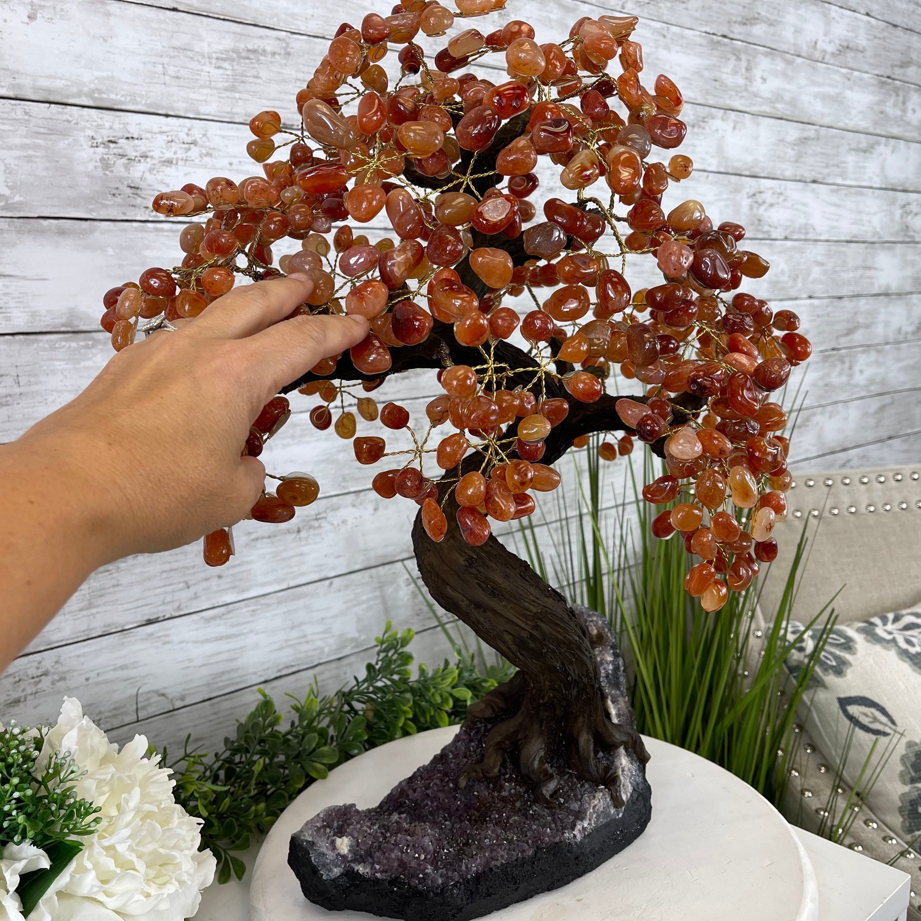 Hand touching the Carnelian Gemstone Tree with red gemstones