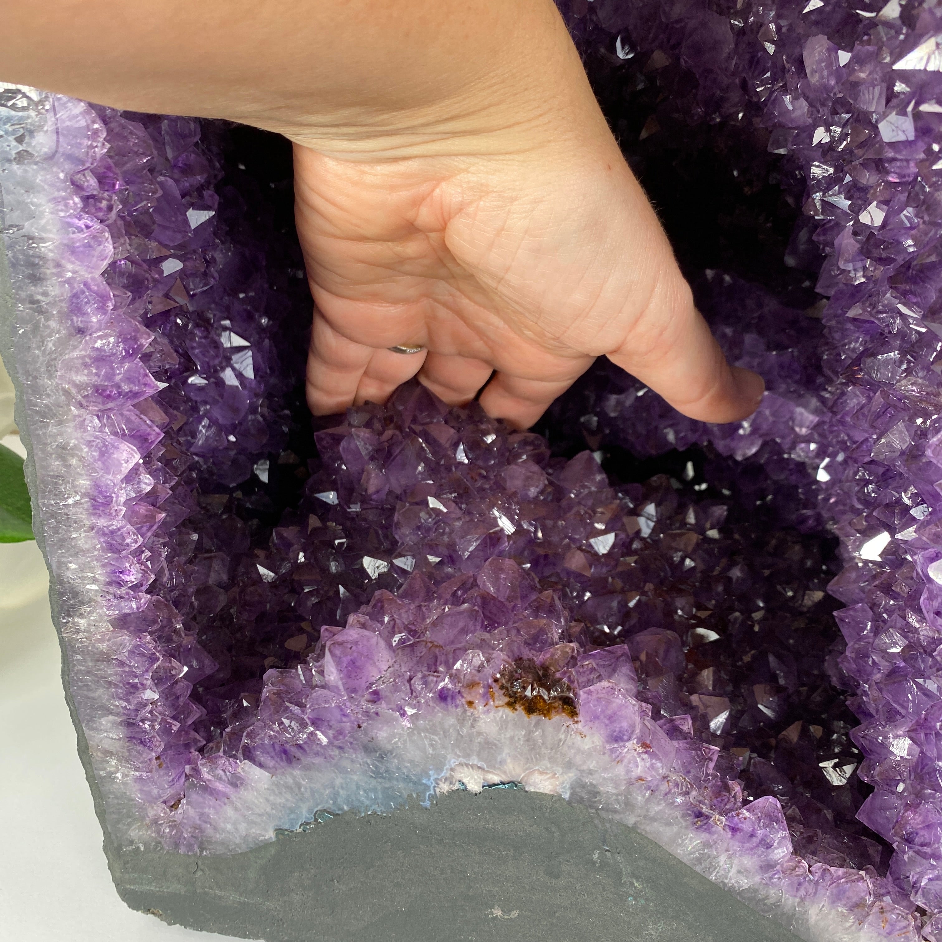 the Extra Quality Brazilian Amethyst Cathedral, 14.6” tall & 43.1 lbs with a woman's hand showing the depth of the piece 
