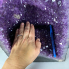 the inner bottom of the Extra Quality Brazilian Amethyst Cathedral, 14.6” tall & 43.1 lbs with a woman's hand and pen for scale 